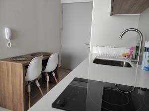 a kitchen with a sink and two white chairs at Departamento Estudio en pleno centro de Temuco in Temuco