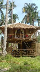 a straw hut with palm trees in the background at Prince John beachfront cottages and Restaurant in San Vicente