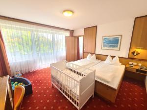 ein Schlafzimmer mit einem Bett und einem Kinderbett in der Unterkunft Thermenhotel Tannenhof - Ihr Wohlfühl-Hotel in Bad Füssing