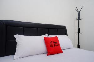 un cuscino rosso su un letto con due cuscini bianchi di RedDoorz Syariah near RS Soeradji Pemuda Klaten a Klaten