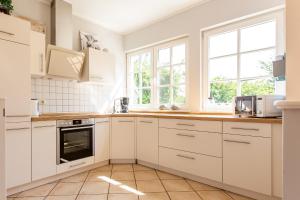 - une cuisine blanche avec des armoires et des fenêtres blanches dans l'établissement Künstlerhaus Rosenthal 02, à Ahrenshoop