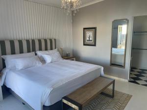 a bedroom with a large white bed and a mirror at Back Home Bed and Breakfast in Graaff-Reinet