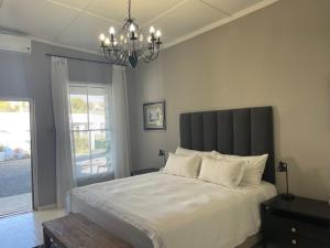 a bedroom with a large white bed with a chandelier at Back Home Bed and Breakfast in Graaff-Reinet