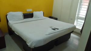 バンガロールにあるHotel Amster Innの白いベッドシーツが備わる客室の大型ベッド1台分です。