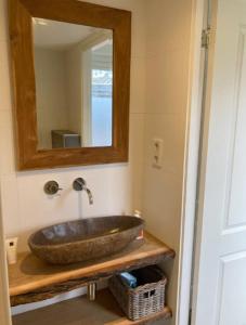 een badkamer met een stenen wastafel en een spiegel bij Guesthouse Salty Life near the beach in Noordwijk aan Zee