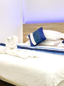 Bett mit weißer Bettwäsche und blauen und weißen Kissen in der Unterkunft Moodhu Surf House in Himmafushi