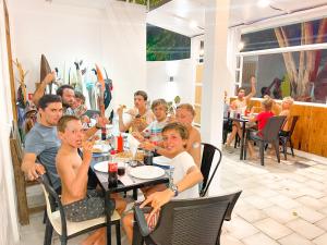 grupa ludzi siedzących przy stole w restauracji w obiekcie Moodhu Surf House w mieście Himmafushi