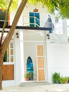 a white house with a door with a window at Moodhu Surf House in Himmafushi