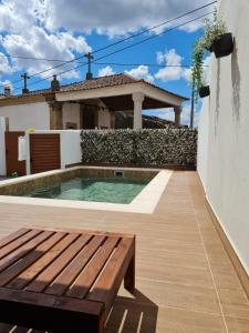 uma piscina com um banco e uma casa em CASA DA CAPELA, Casas Bem Haja. em São Miguel de Acha