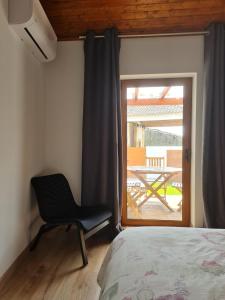 um quarto com uma cadeira em frente a uma janela em CASA DA CAPELA, Casas Bem Haja. em São Miguel de Acha