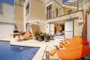 a house with a pool with chairs and a table at Razzett Luna Holiday Home in Xagħra