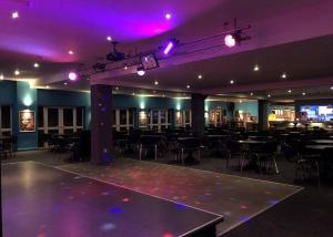 a room with tables and chairs and purple lights at Monkey Tree Holiday Park in Newquay