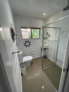 uma casa de banho com um WC e uma cabina de duche em vidro. em Relax at Trinity Beach Getaway, Blue Lagoon, Trinity Beach em Trinity Beach