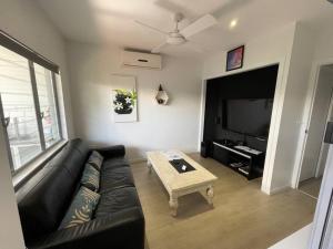 uma sala de estar com um sofá de couro preto e uma mesa de centro em Relax at Trinity Beach Getaway, Blue Lagoon, Trinity Beach em Trinity Beach