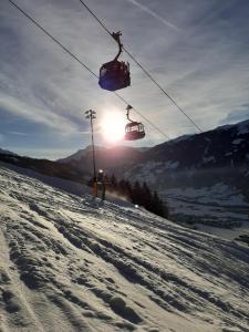 een skilift op een besneeuwde helling met de zon bij Apart Bergauf in Rohrberg