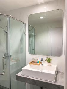 a bathroom with a sink and a shower and a mirror at Miloft Sathorn Hotel in Bangkok