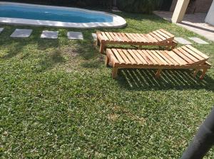 two wooden benches sitting next to a swimming pool at Rinacasaquinchoypile in Paraná