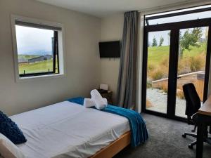 ein Schlafzimmer mit einem Bett und einem großen Fenster in der Unterkunft Beautiful Lake and Alpine Views - Queenstown in Queenstown