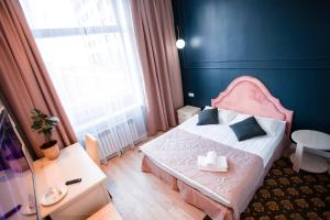 a bedroom with a bed with a pink headboard and a window at ARENA Hotel in Astana