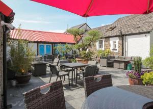 a patio with tables and chairs and a red umbrella at Noble Court Holiday Park in Narberth