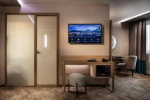 een hotelkamer met een bureau en een tv aan de muur bij -- ESTE PARK HOTEL -- part of Urban Chic Luxury Design Hotels - Parking & Compliments - next to Shopping & Dining Mall Plovdiv in Plovdiv