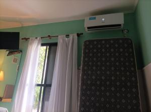 1 Schlafzimmer mit einem Fenster mit Vorhängen und Klimaanlage in der Unterkunft Rinacasaquinchoypile in Paraná