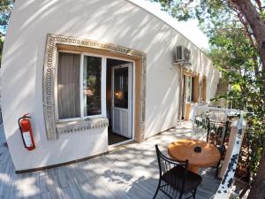 Casa blanca pequeña con mesa de madera y sillas en Atillas Getaway, en Selçuk