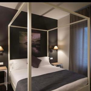 - une chambre avec un lit à baldaquin et des draps blancs dans l'établissement Hotel B&B il Mosaico, à Sirmione