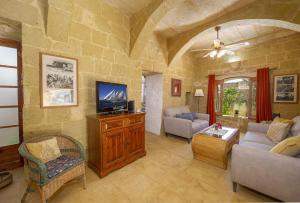 a living room with a couch and a tv at Oleandra Holiday Home in Għasri