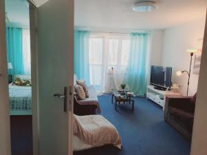 um quarto com uma cama e uma televisão e um quarto com cortinas azuis em Centrum Łucka 15 Parking Basen em Varsóvia