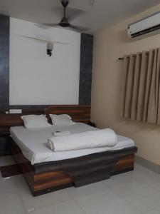 a bedroom with a bed with white sheets and a fan at hotel sagnik in Murshidābād