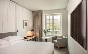 a hotel room with a bed and a chair and a window at Le Grand Pavillon Chantilly in Chantilly