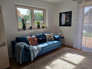 ein blaues Sofa im Wohnzimmer mit zwei Fenstern in der Unterkunft Gemütliche Premium Ferienwohnung mit Terrasse nähe S-Bahn in Burgthann