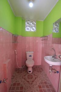 a pink bathroom with a toilet and a sink at Joval Homestay in Coron