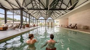 duas pessoas a nadar numa piscina num edifício em Le Grand Pavillon Chantilly em Chantilly