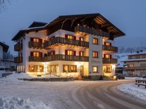 een groot gebouw in de sneeuw 's nachts bij Hotel Dolomiten in Monguelfo