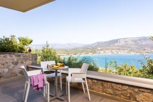 a table and chairs on a balcony with a view of the ocean at Princess Kyniska Suites in Plytra