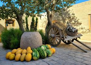 a pile of pumpkins and watermelons next to a wagon at madrasah Polvon-Qori boutique hotel in Khiva