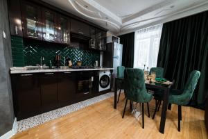 cocina con mesa de comedor y sillas verdes en Сдам 2-х комнатную квартиру посуточно, en Uralsk
