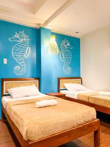 duas camas num quarto com cavalos-marinhos pintados na parede em Amos Portside Inn em El Nido