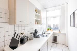 - une cuisine blanche avec des placards blancs et un évier dans l'établissement Gemütliches Apartment im Herzen Kiels, à Kiel