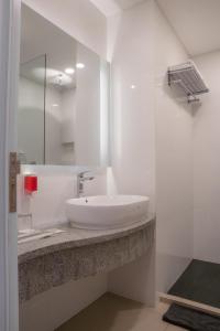 Grand G7 Hotel Pasar baru في جاكرتا: حمام أبيض مع حوض ومرآة