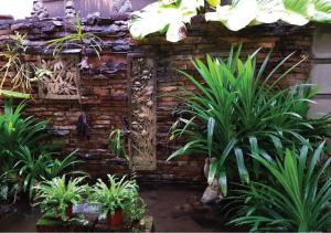 een tuin met planten voor een bakstenen muur bij Pakin house in Ban Nua Khlong
