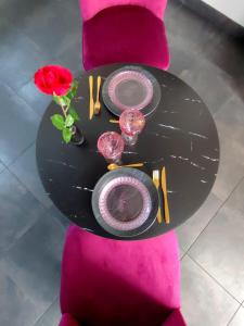 une table avec des assiettes et des verres et une rose sur elle dans l'établissement Love Room à Montargis, à Montargis