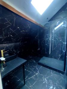La salle de bains est pourvue d'un sol en marbre noir et d'un lavabo. dans l'établissement Love Room à Montargis, à Montargis