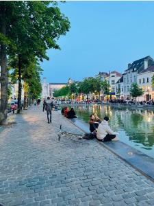 un grupo de personas sentadas en una acera junto a un río en Down Town Spacious Loft with Private Parking, en Bruselas