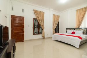 um quarto com uma cama grande e uma televisão em RedDoorz Syariah near Universitas Putra Indonesia Padang em Kampungdurian