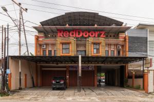um edifício com uma porta vermelha z assinar nele em RedDoorz Syariah near Universitas Putra Indonesia Padang em Kampungdurian