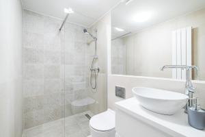 a white bathroom with a sink and a shower at E-Stay Noclegi w Bydgoszczy in Bydgoszcz