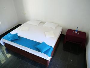 ein weißes Bett mit blauen Kissen in einem Zimmer in der Unterkunft Secret Paradise in Varkala